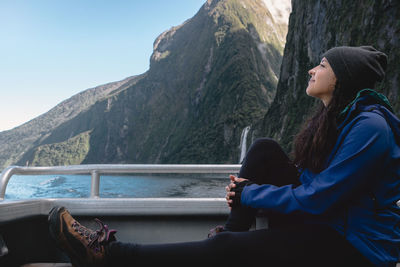 Side view of woman looking at mountains against sky