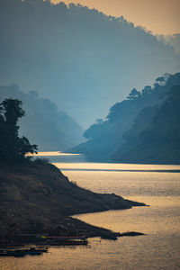 Scenic view of lake by mountains during sunset