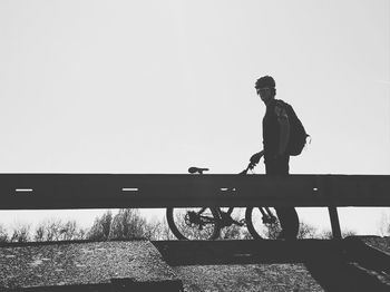 Man standing on wall against clear sky