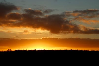 Silhouette landscape against dramatic sky during sunset