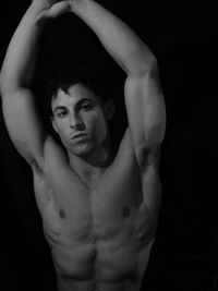 Portrait of shirtless muscular build model against black background