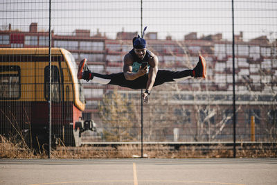 African man using mobile phone while jumping on sports court