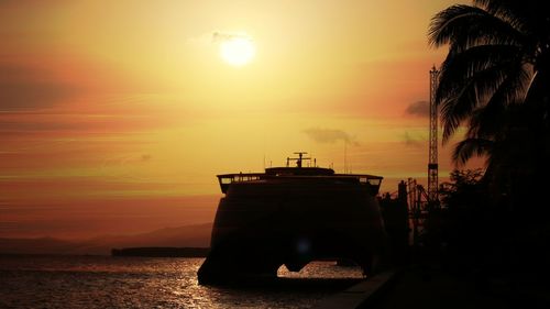 Silhouette sailboat in sea against sky during sunset