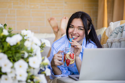 Young woman using mobile phone while sitting at home