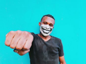 Portrait of young man wearing mask against blue background