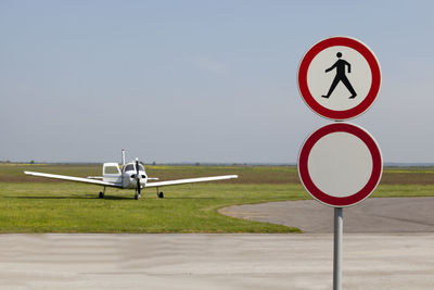 Road sign at airport runway against clear sky