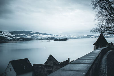 Scenic view of lake by buildings against sky during winter