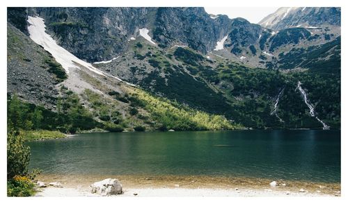 Scenic view of lake by mountain against sky