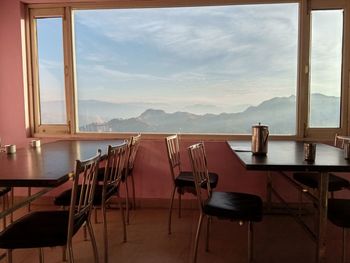 Empty chairs and tables in restaurant against sky