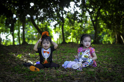 Cute siblings sitting on grass at park