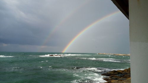 Scenic view of rainbow over sea against sky