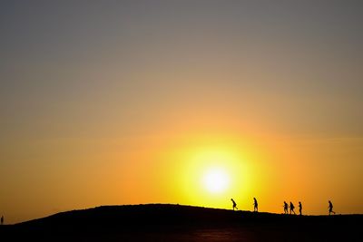 Silhouette people on land against clear sky during sunset