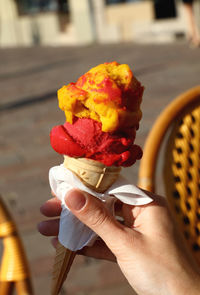 Cropped image of hand holding ice cream cone on street