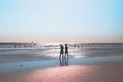 Silhouette men on beach against clear sky
