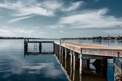 Pier on sea against cloudy sky