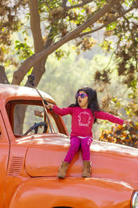 Girl taking selfie while sitting on abandoned car