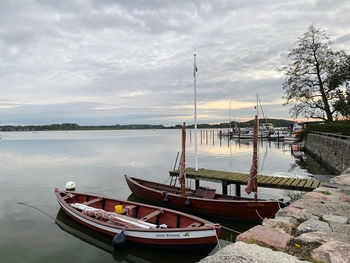Sailboats moored on lake against sky