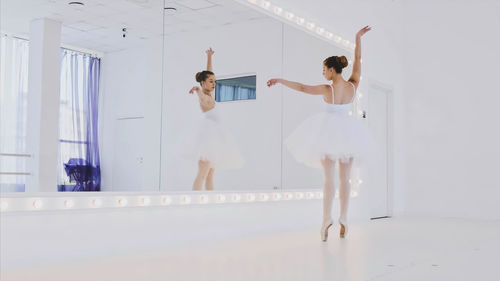 Ballerina looking in mirror while dancing at studio