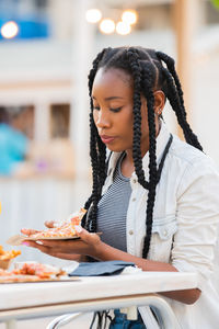 Woman holding pizza while sitting in restaurant