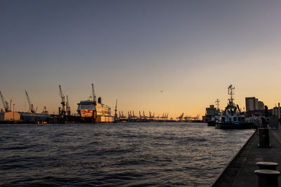 Scenic view of harbour in hamburg against sky during sunset