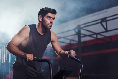 Side view of young man standing in gym