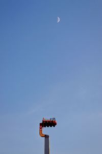 Low angle view of illuminated lighting equipment against clear blue sky