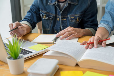 Midsection of man reading book on table