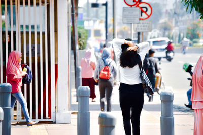 Rear view of people walking on road along buildings