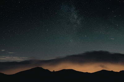 Scenic view of silhouette mountains against sky at night