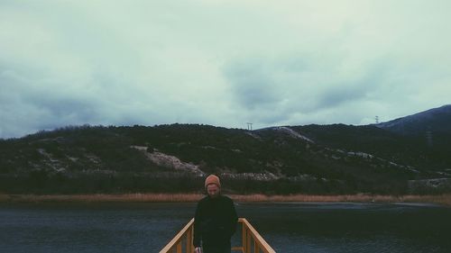 Rear view of man standing by lake