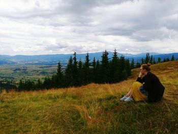 Women sitting on field against sky