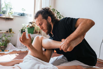 Midsection of man sitting on table at home