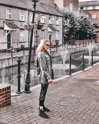 Full length of woman standing on footpath against building in city