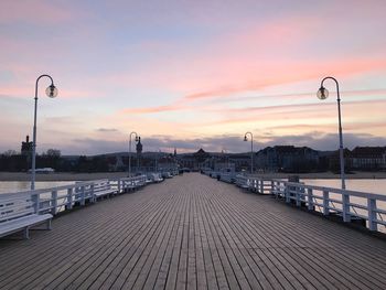 Street by pier against sky during sunset