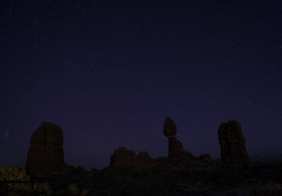 Low angle view of rock formation against sky at night