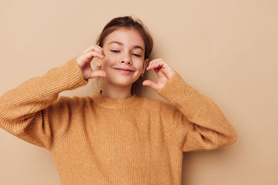 Girl gesturing against beige background