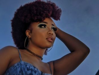 Portrait of young woman looking away against sky