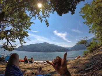 People by lake against sky