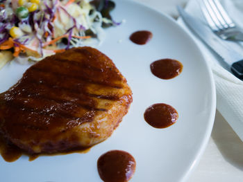 Close-up of pork chop with barbeque sauce in plate served on table