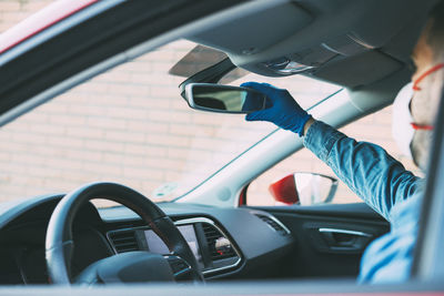 Man with gloves adjusting the mirror of his car. drive with covid-19.