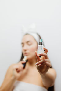 Midsection of woman holding camera over white background