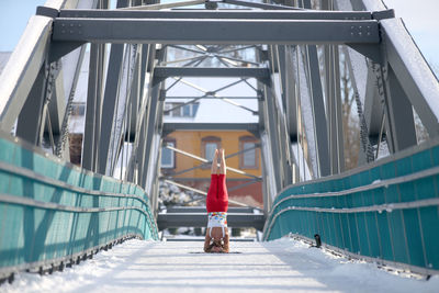 Rear view of woman doing headstand on bridge