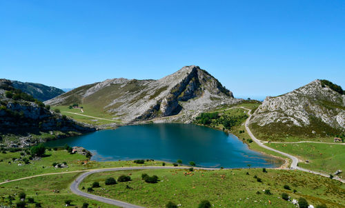 Scenic view of lake and mountains against clear blue sky