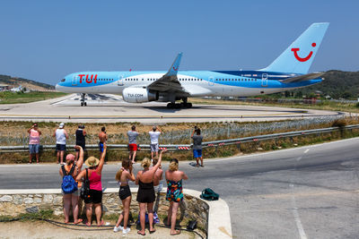 People at airplane against clear sky