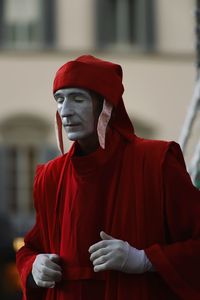 Midsection of person holding red standing against wall