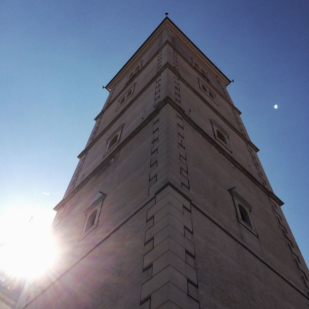 architecture, building exterior, built structure, low angle view, sun, tower, tall - high, clear sky, lens flare, sunbeam, sunlight, city, sky, skyscraper, blue, travel destinations, famous place, modern, building, outdoors