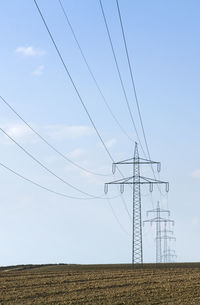 Low angle view of electricity pylon on field against sky