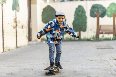 Full length portrait of boy skateboarding on footpath