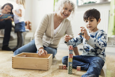 Happy teacher looking at boy stacking blocks at day care center