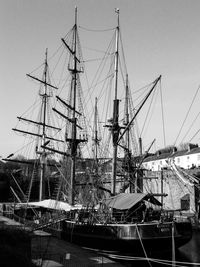 Sailboat moored at harbor against clear sky